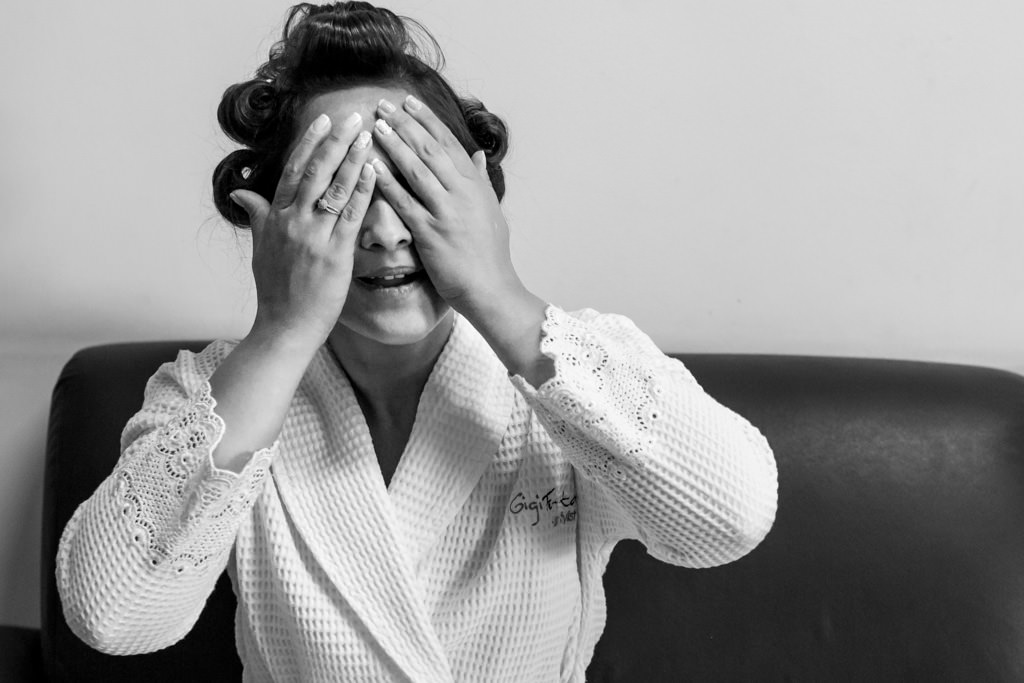 Making of da noiva luciana de bobs no cabelo, com as mãos tampando os olhos com seu lindo roupão