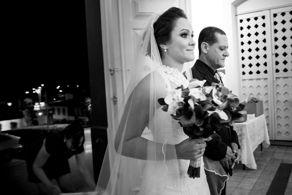 a entrada triunfal da noiva, segurando o seu lindo buquê ao lado do seu pai