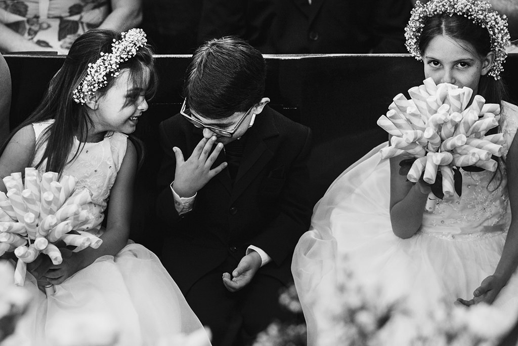 os pagens e as daminhas sentadas sorrindo e olhando para o buquê de Marshmallow