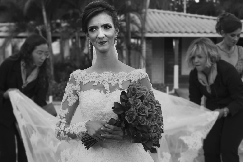 A linda noiva Thayane, segurando seu buque e o cerimonial preparando o seu vestido para a grande entrada;