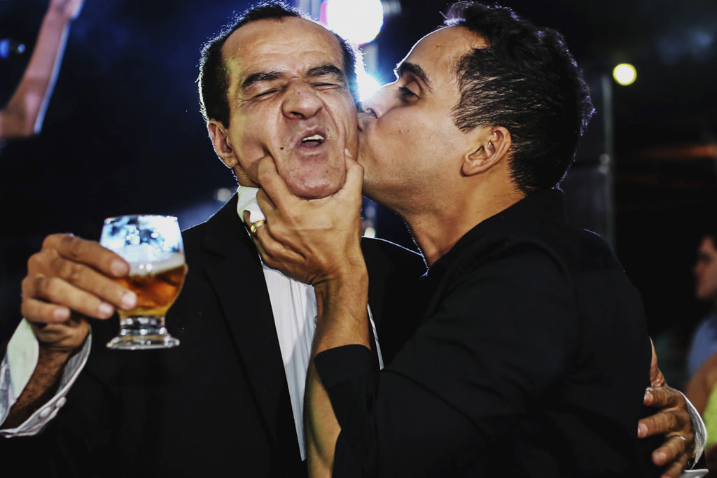 o convidado beijando o rosto do pai da noiva durante a festa