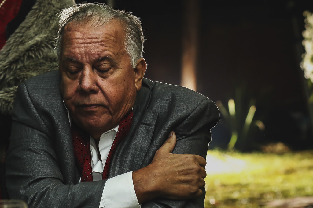 o pai do noivo fim de festa, com os braços entrelaçados, quase cochilando