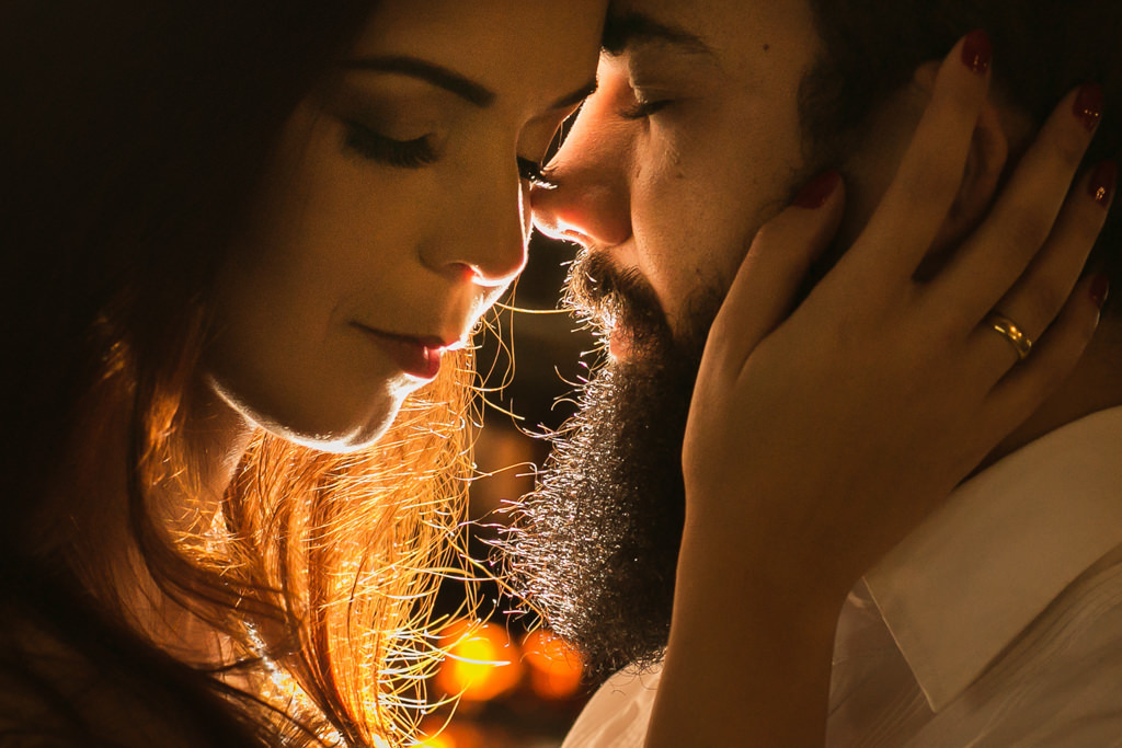 ao fundo um fogão a lenha, o fogo contorna o rosto dos noivos