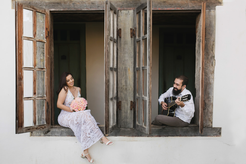 Sentado na janela Julimare a noiva admira Fernando tocando violão
