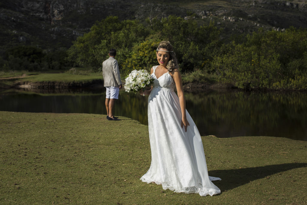 A noiva Paula segurando o seu lindo buque, e Bruno ao fundo admirando a paisagem