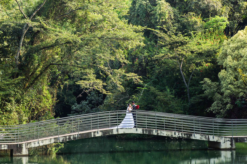 O casal João Carlos e Carina abraços no meio da ponte de um lindo lago esverdiado
