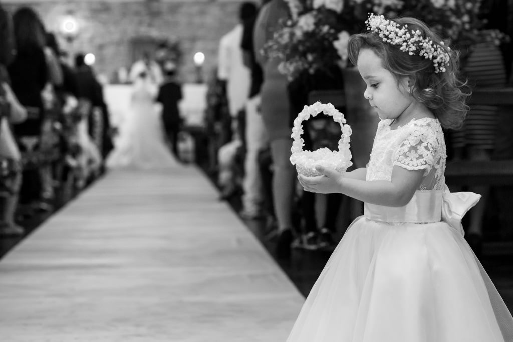 A bela Maria Luiza (filha dos noivos Adelson e Nayara) segurando a porta aliança com seus pais ao fundo no altar da igreja