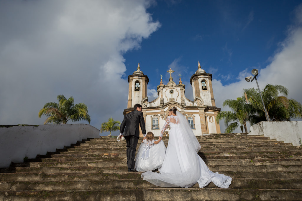 Segurando as mãos de Maria Luiza, Adelson e Nayara  ajudando a sua filhinha subir as escadarias da igreja