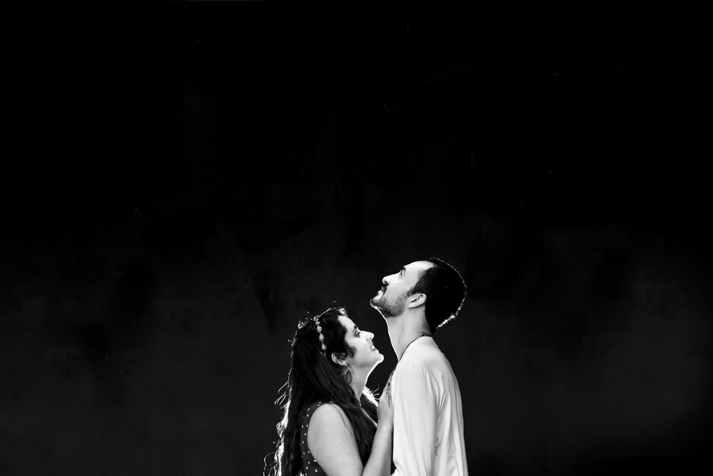 Embaixo de uma luminária Thammy olhado para Christian a luz contornado seus rostos