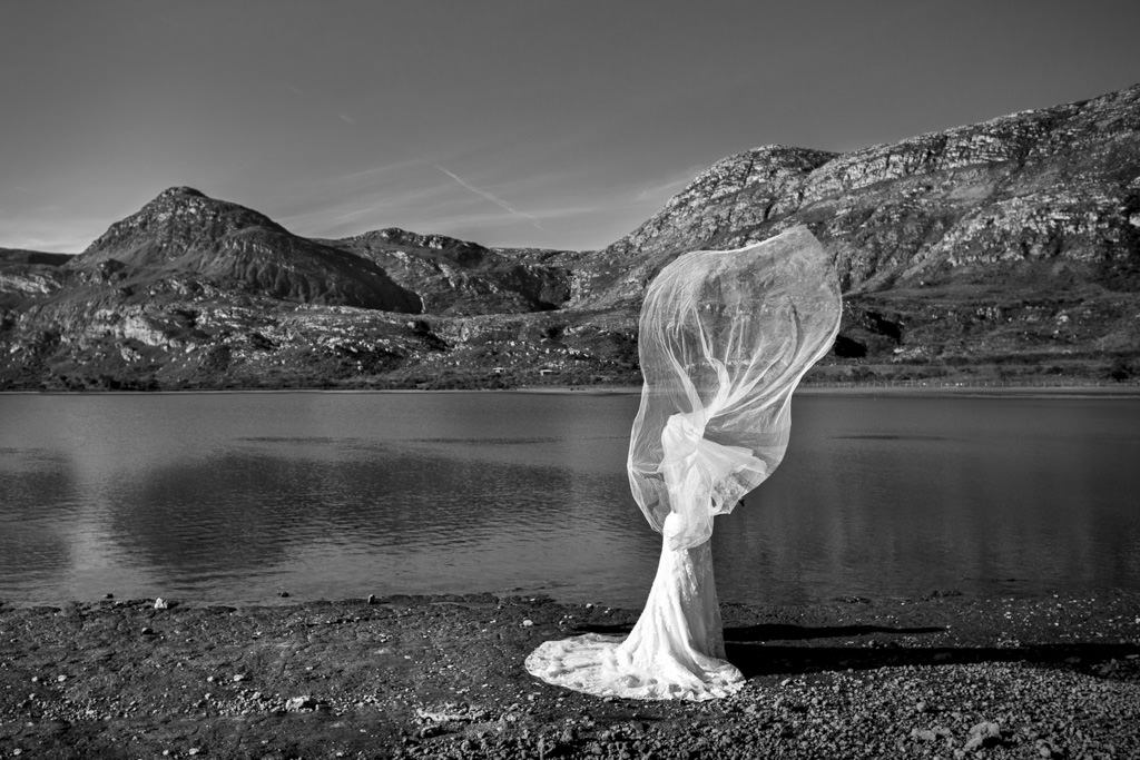 o véu voando do lindo vestido da noiva, tampou a noiva o que a transformou em uma linda escultura
