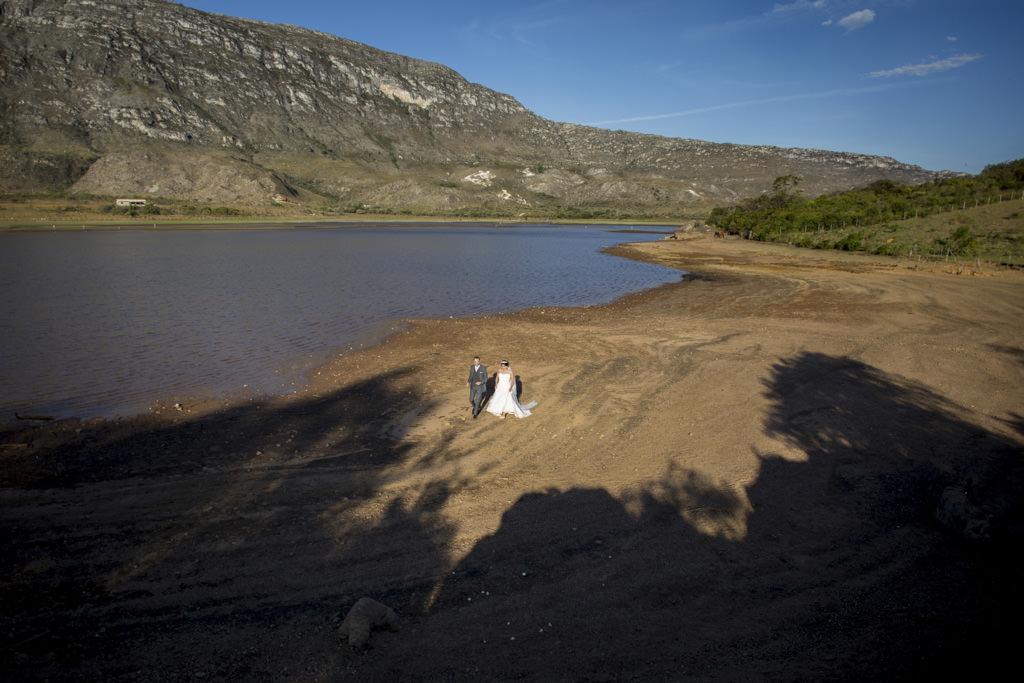 os noivos caminhando na praia do lago da lapinha da serra uma vista ampla