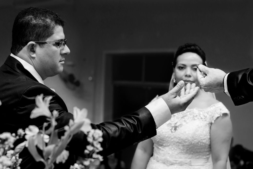 A troca de aliança, momento em que marcelo recebe a aliança da mão do pastor sob o olhar atendo da noiva liliam