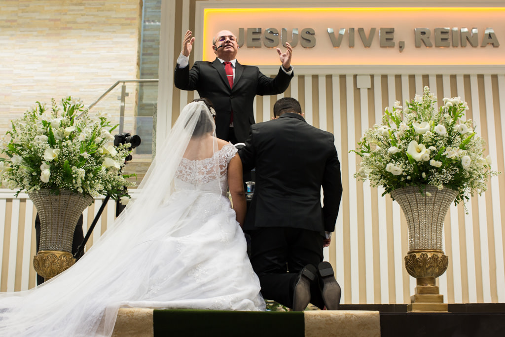 ajoelhados no altar os noivos recebem a benção do pastor