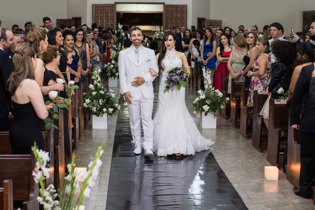 O noivos rafaela e henrique no tapete preto da igreja santa luzia rumo ao altar