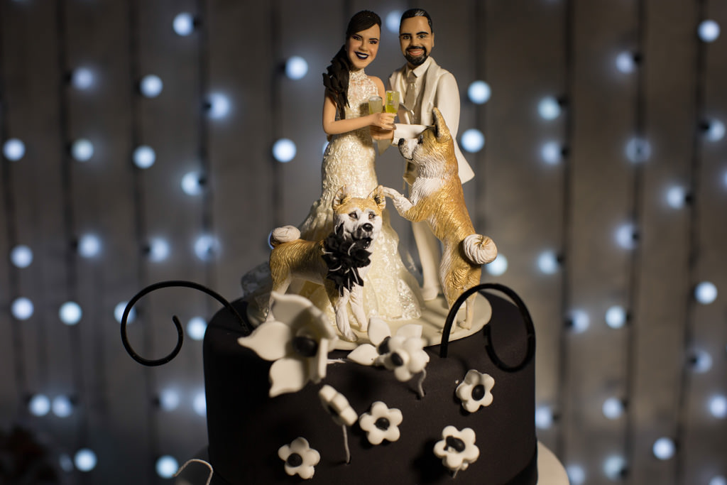 o biscuit em cima do bolo de casamento representado pelo casal de noivos e seu lindos akitas