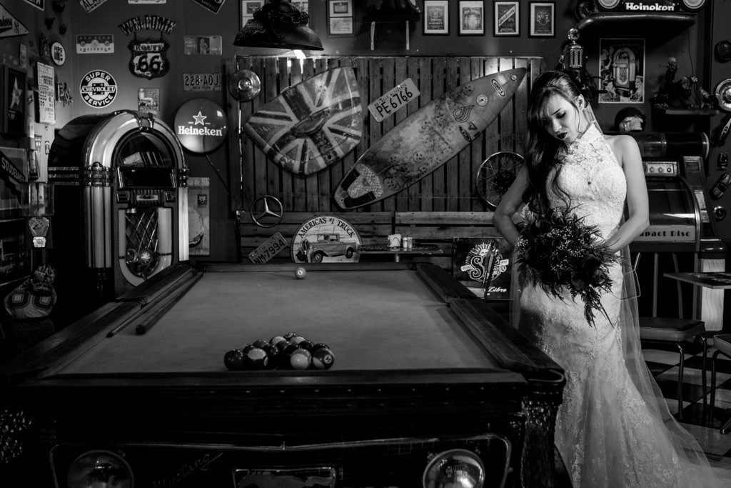 ao lado de uma mesa de sinuca Rafaela exibe o seu lindo vestido de noiva e seu buque preto
