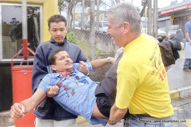 cobrador de ônibus é baleado durante assalto.  Motorista para diante de hospital e pessoalmente coloca o companheiro de trabalho na maca.