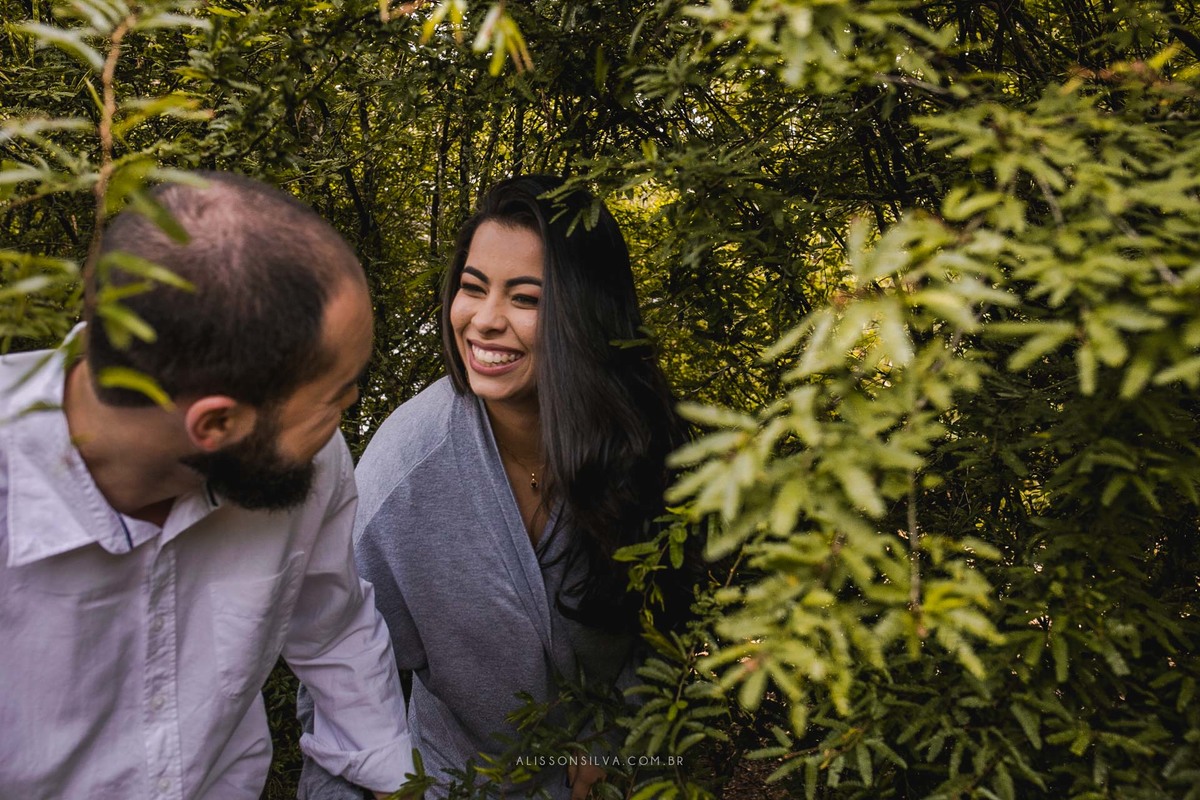 Casal em meio a árvores, caminhado de mãos dadas.