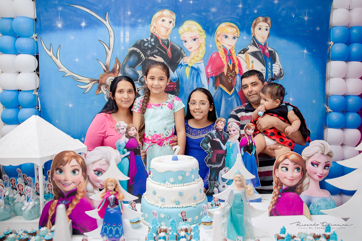 A família toda atrás da mesa do bolo posando para a foto