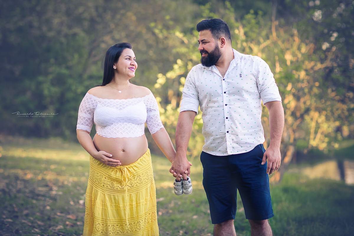 Orgulho do papai e da mamãe exibindo o sapatinho do bebê