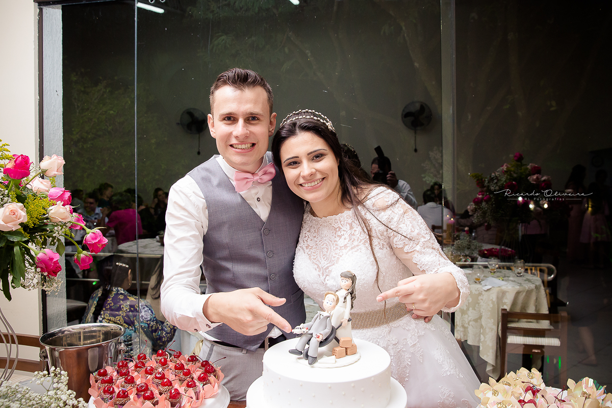 Noivos tirando foto atras da mesa do bolo