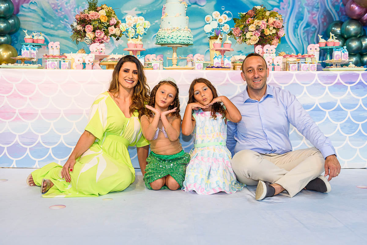 pose sentada da menina vestida de sereia com seus pais e sua irmã