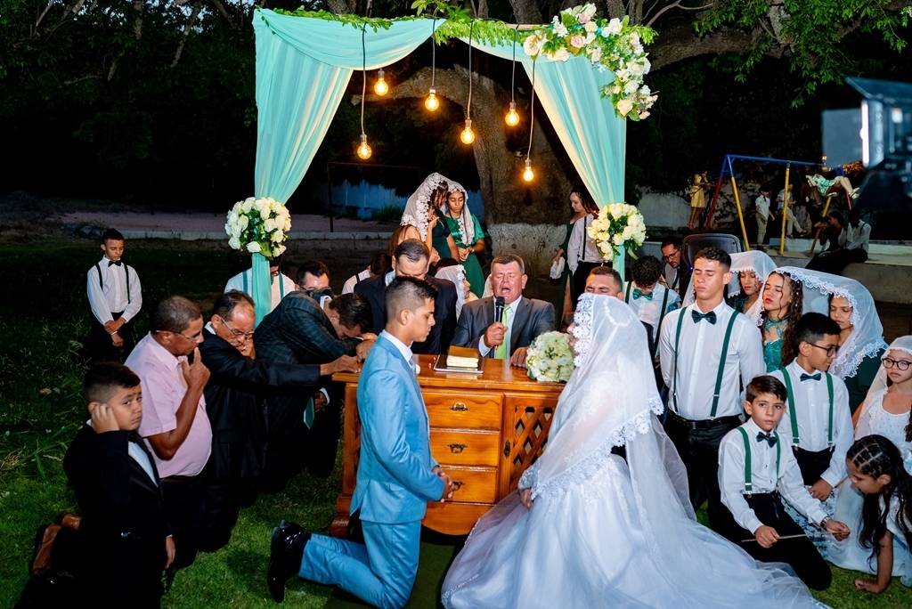 casal ajoelhado em oração em casamento ao ar livre