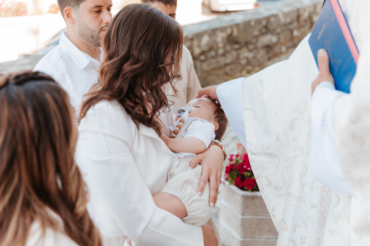 Registo fotográfico profissional de família cheia de afeto e conexão no batizado.