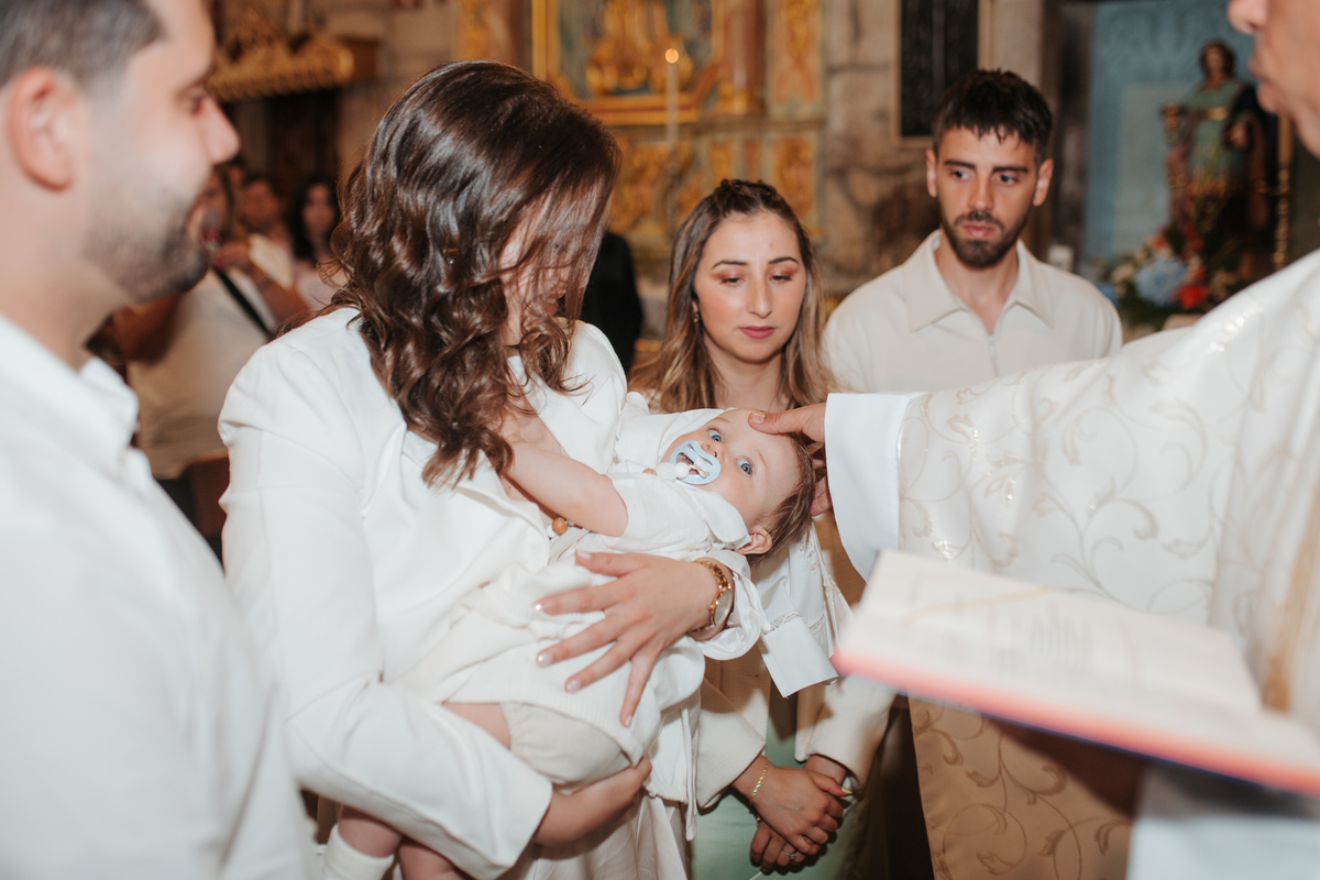 Registo fotográfico profissional de família cheia de afeto e conexão no batizado.
