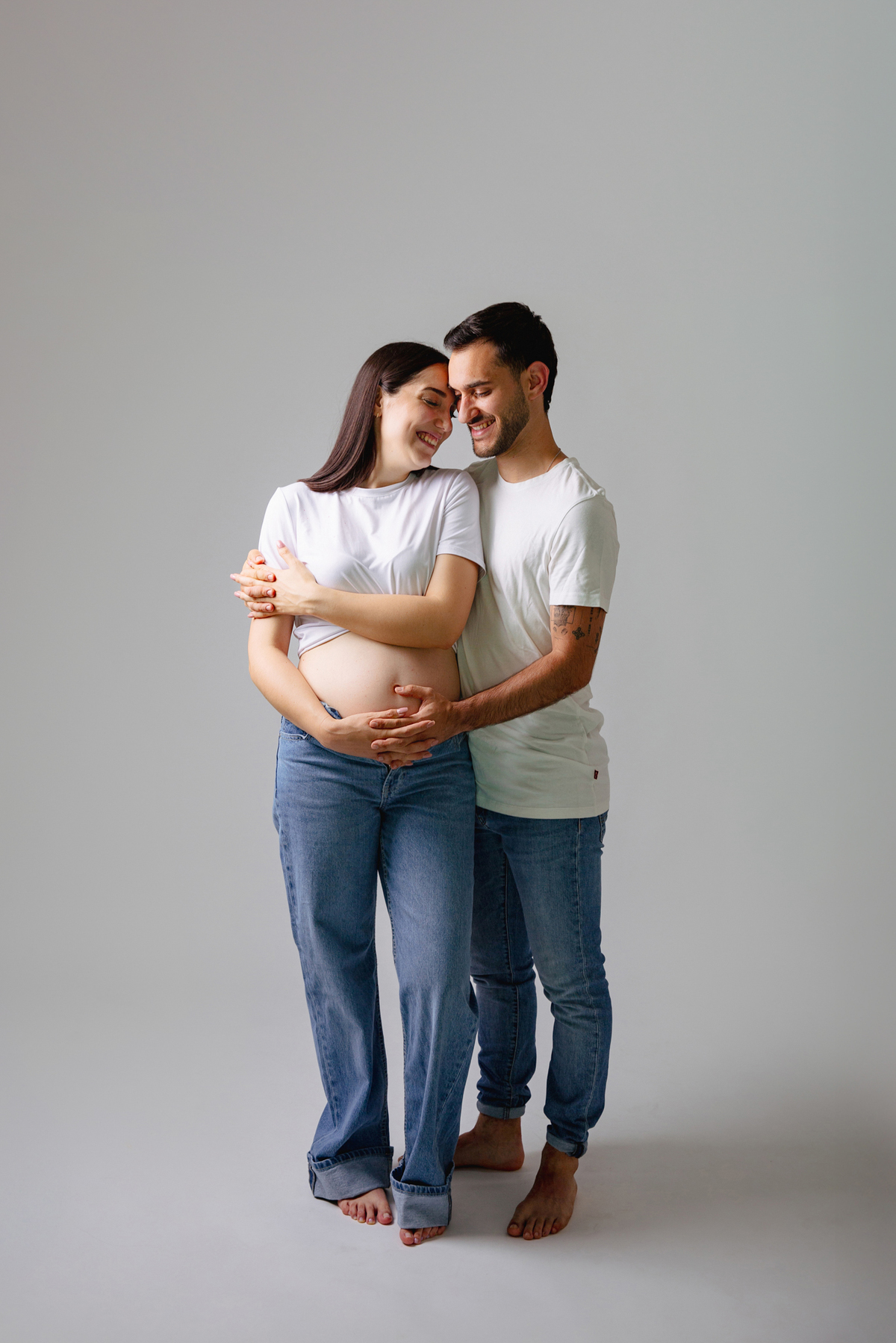 Fotografia de casal em estúdio para celebrar a revelação da gravidez com afeto.