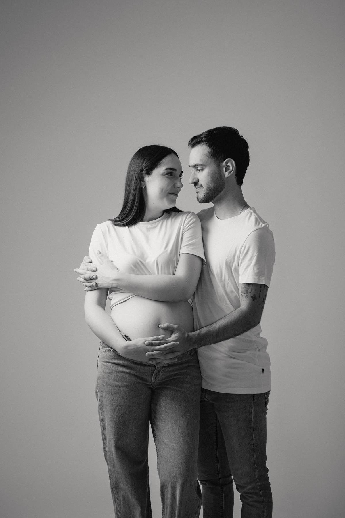 Fotografia de casal em estúdio para celebrar a revelação da gravidez com afeto.