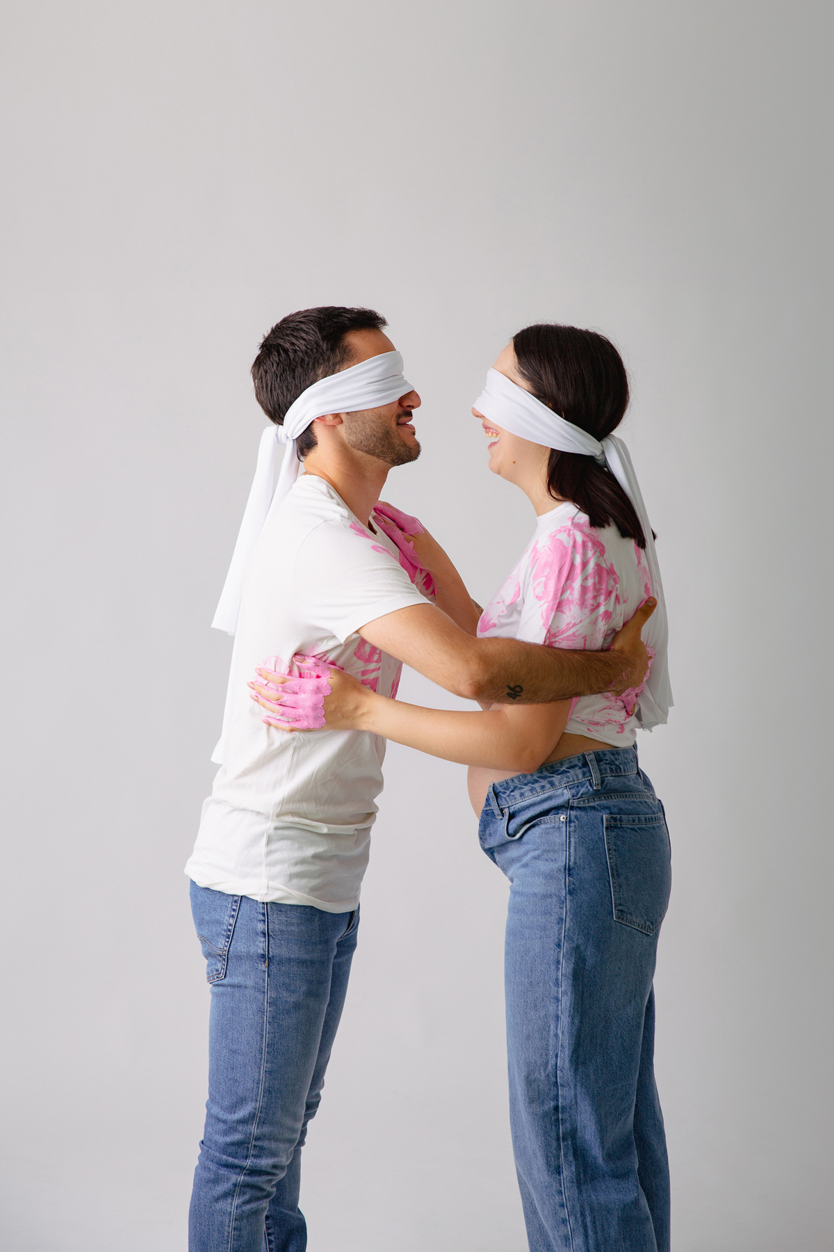 Fotografia de casal em estúdio para celebrar a revelação da gravidez com afeto.