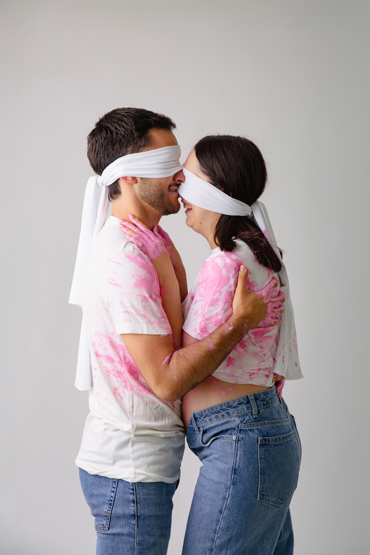 Fotografia de casal em estúdio para celebrar a revelação da gravidez com afeto.