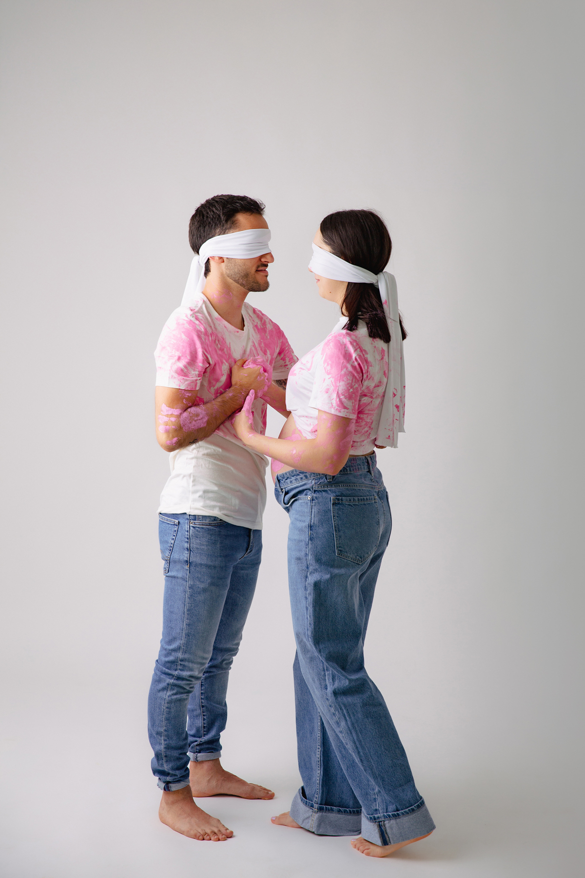 Fotografia de casal em estúdio para celebrar a revelação da gravidez com afeto.