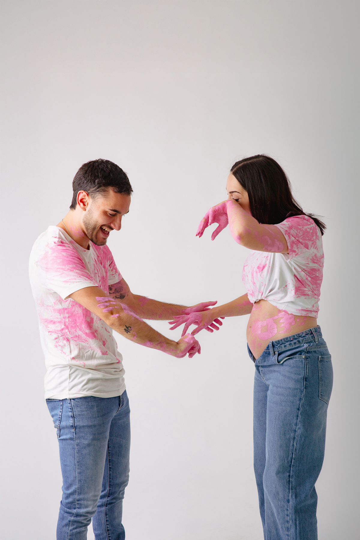 Fotografia de casal em estúdio para celebrar a revelação da gravidez com afeto.