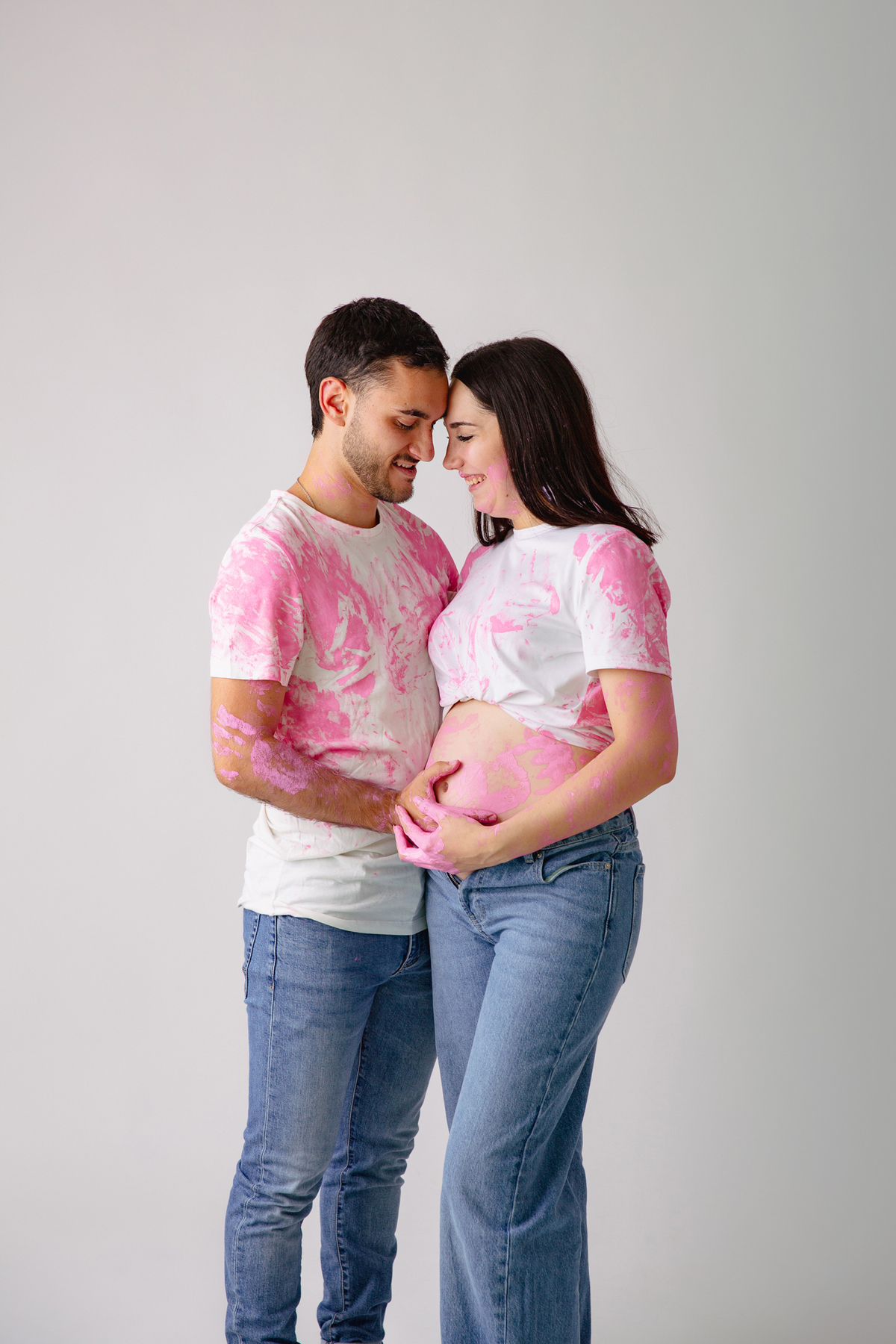 Fotografia de casal em estúdio para celebrar a revelação da gravidez com afeto.
