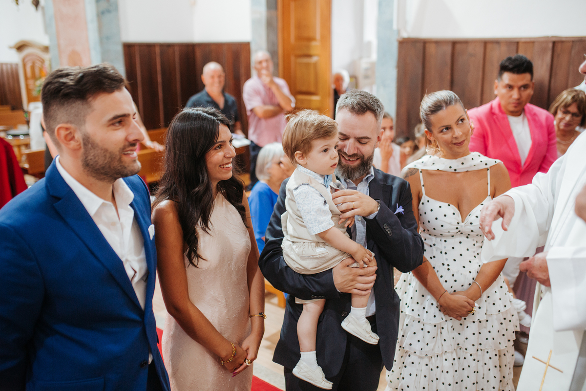 Momento de afeto e cumplicidade familiar na reportagem fotográfica de batizado.