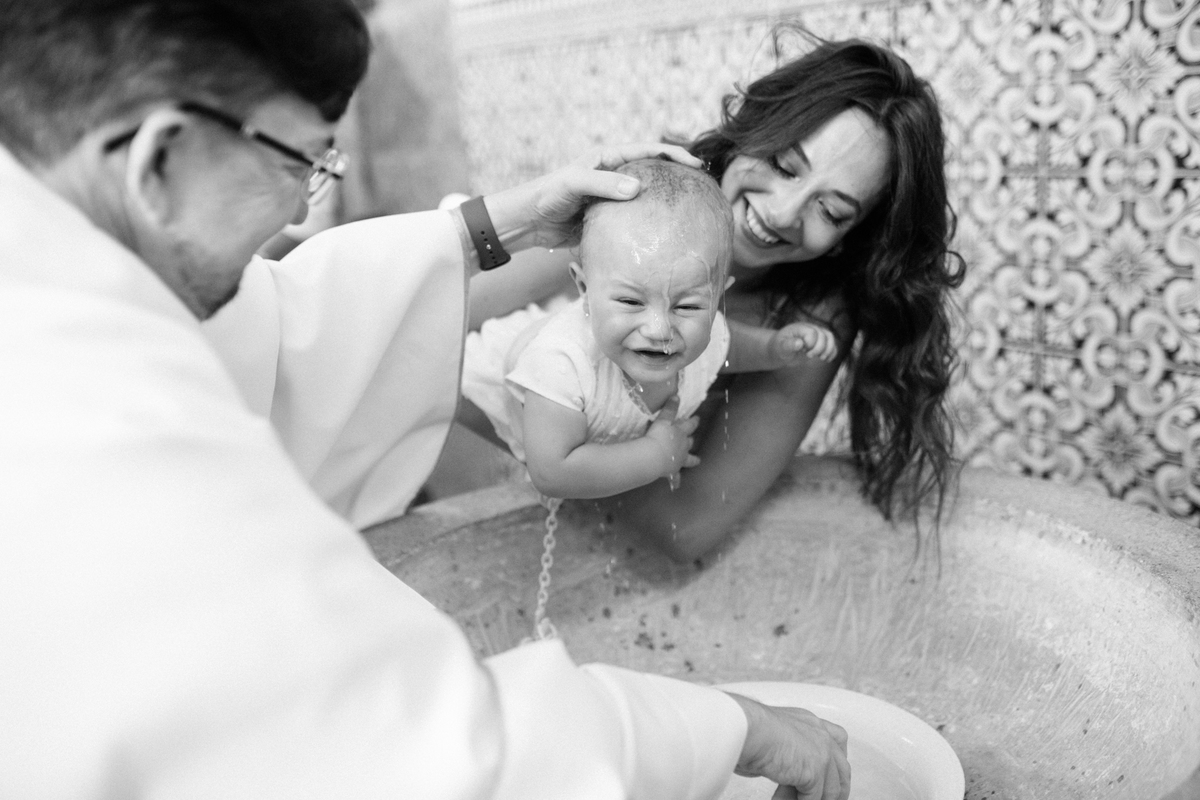 Momento de cumplicidade e sorrisos na reportagem fotográfica de batizado de família.