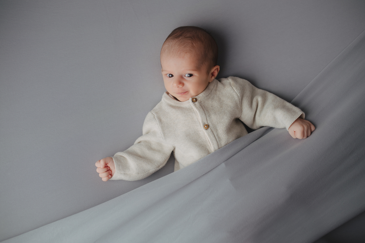 Fotografia newborn com foco na expressão doce e serena do recém-nascido aos 27 dias.