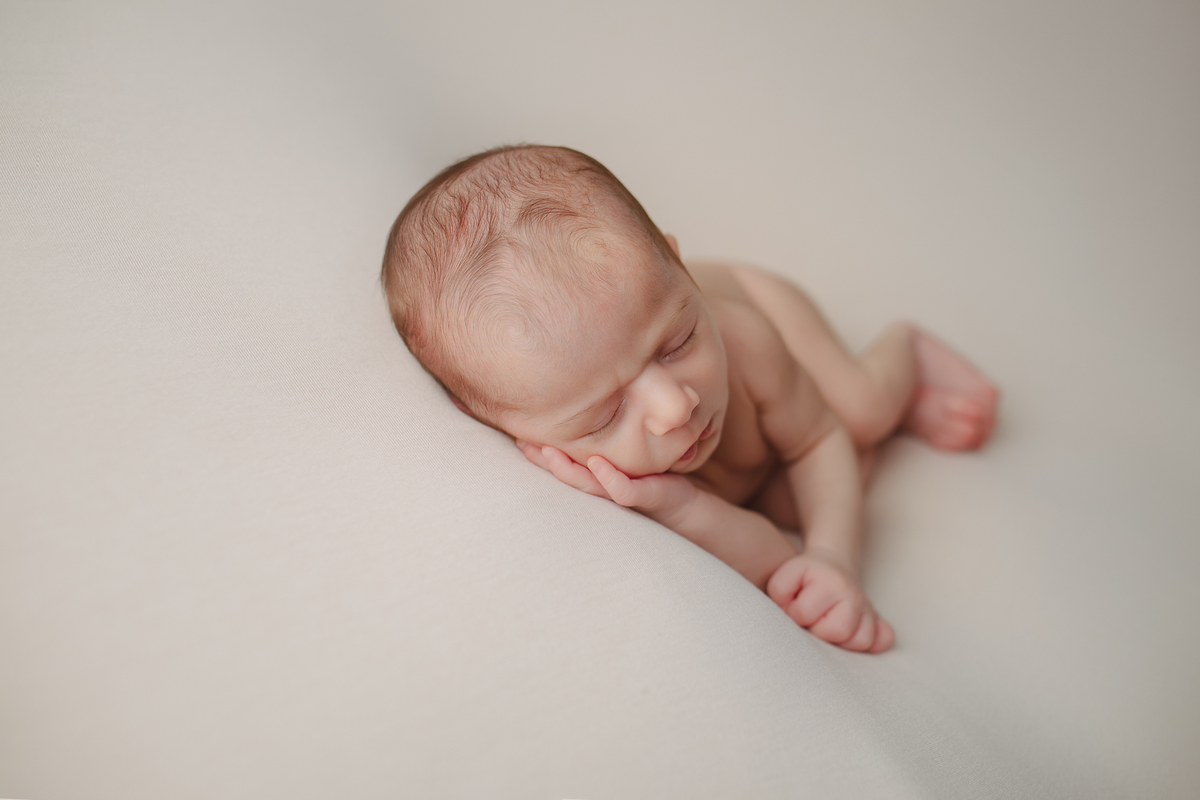 Fotografia newborn com foco na expressão doce e serena do recém-nascido aos 27 dias.