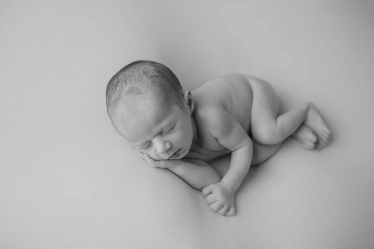 Fotografia newborn com foco na expressão doce e serena do recém-nascido aos 27 dias.