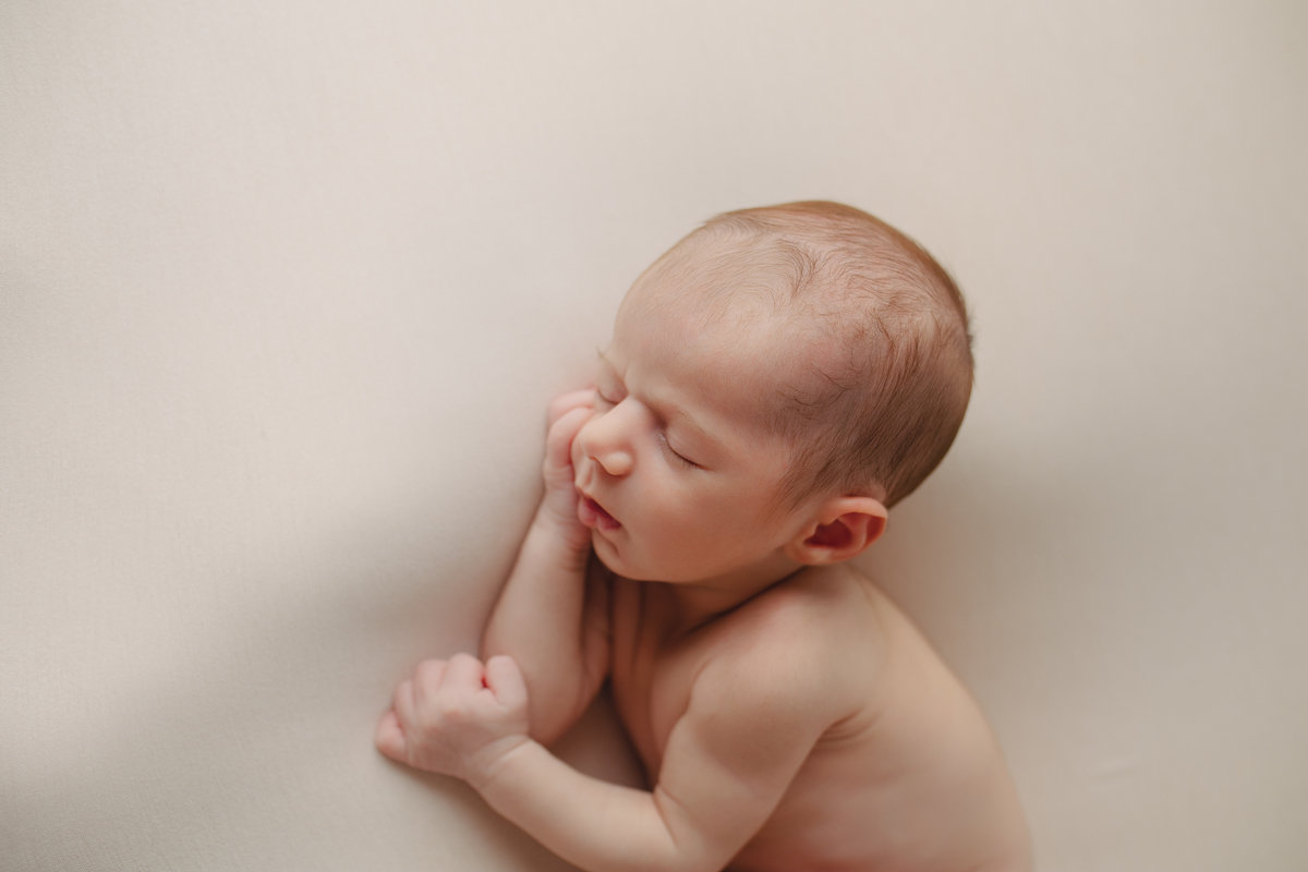 Fotografia newborn com foco na expressão doce e serena do recém-nascido aos 27 dias.