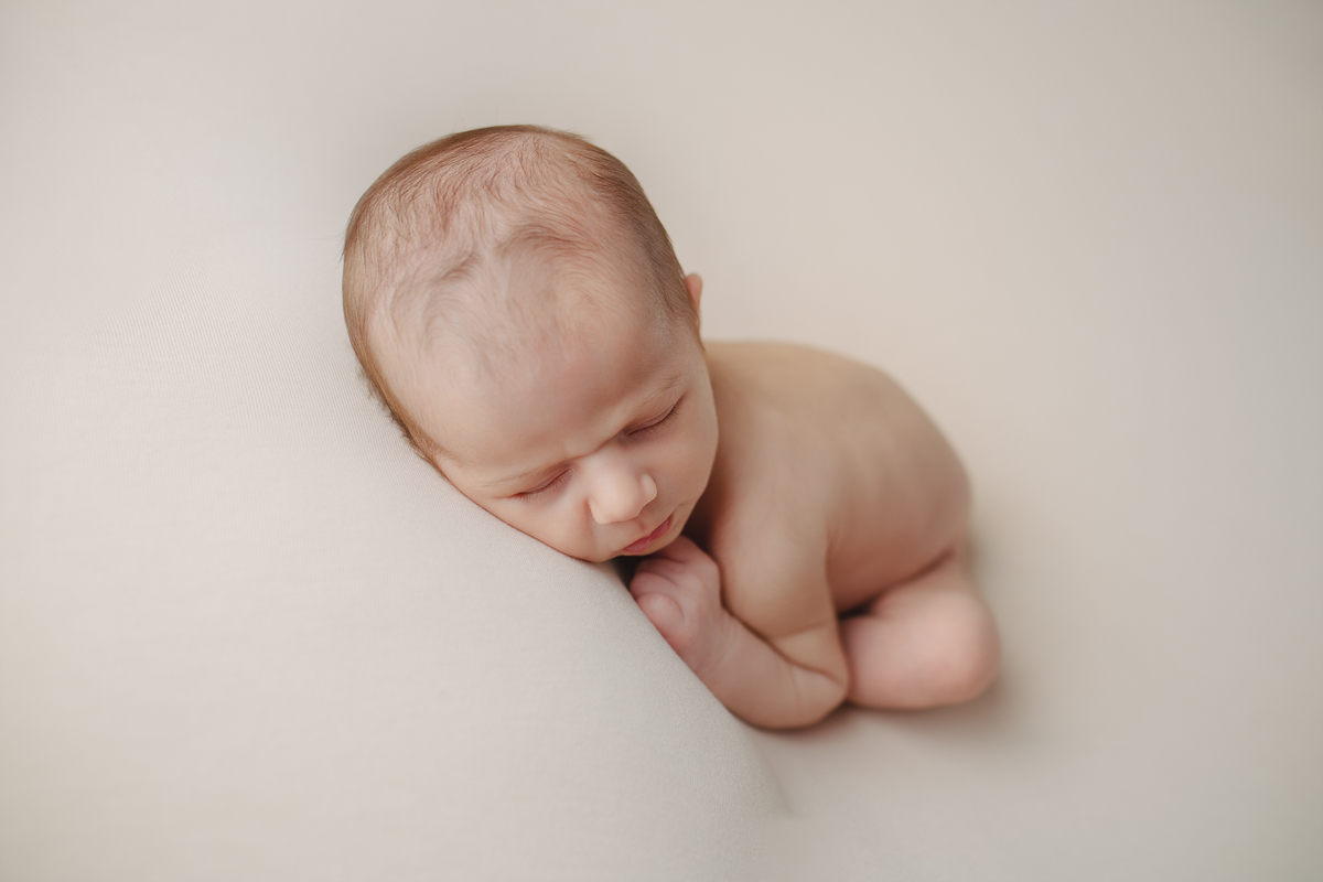Fotografia newborn com foco na expressão doce e serena do recém-nascido aos 27 dias.