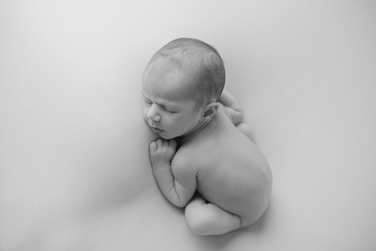 Fotografia newborn com foco na expressão doce e serena do recém-nascido aos 27 dias.