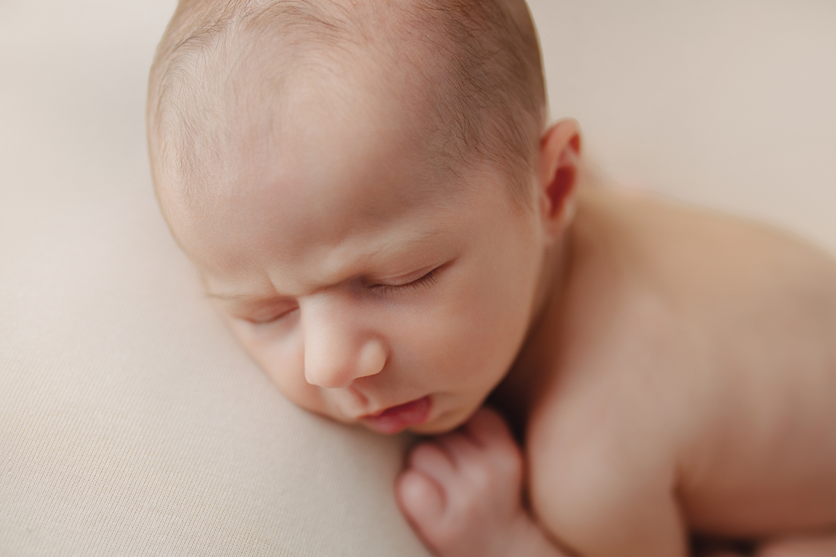 Fotografia newborn com foco na expressão doce e serena do recém-nascido aos 27 dias.