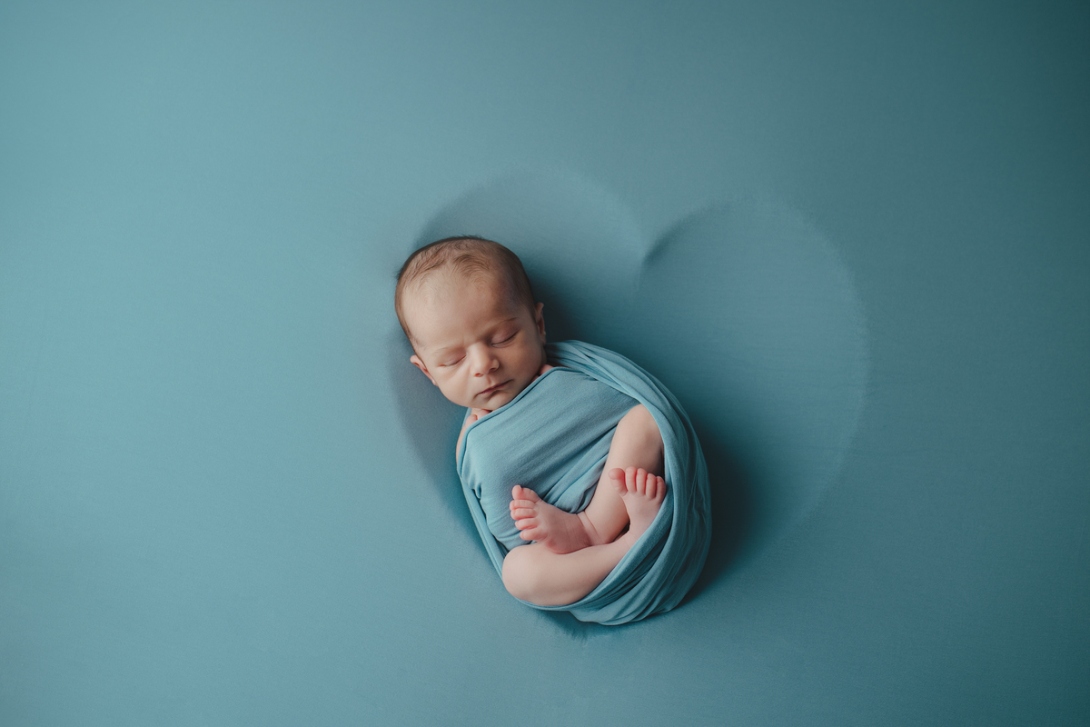 Fotografia newborn com foco na expressão doce e serena do recém-nascido aos 27 dias.