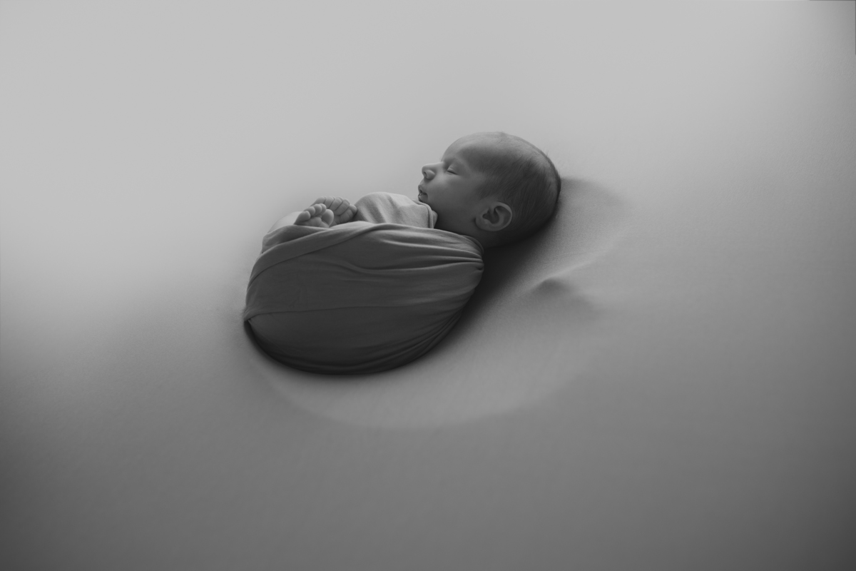 Fotografia newborn com foco na expressão doce e serena do recém-nascido aos 27 dias.