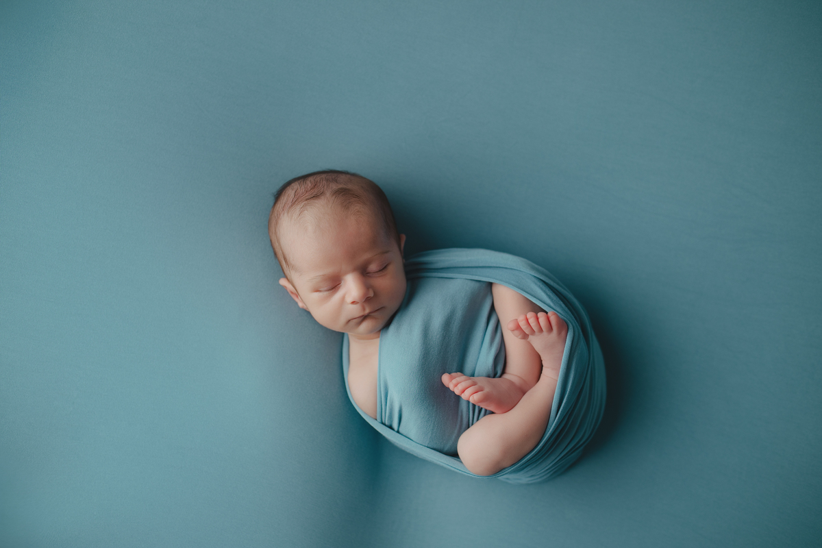 Fotografia newborn com foco na expressão doce e serena do recém-nascido aos 27 dias.