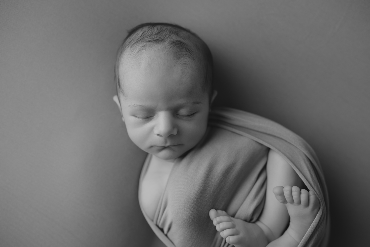 Fotografia newborn com foco na expressão doce e serena do recém-nascido aos 27 dias.