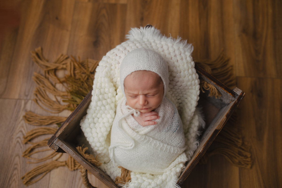 Fotografia newborn com foco na expressão doce e serena do recém-nascido aos 27 dias.
